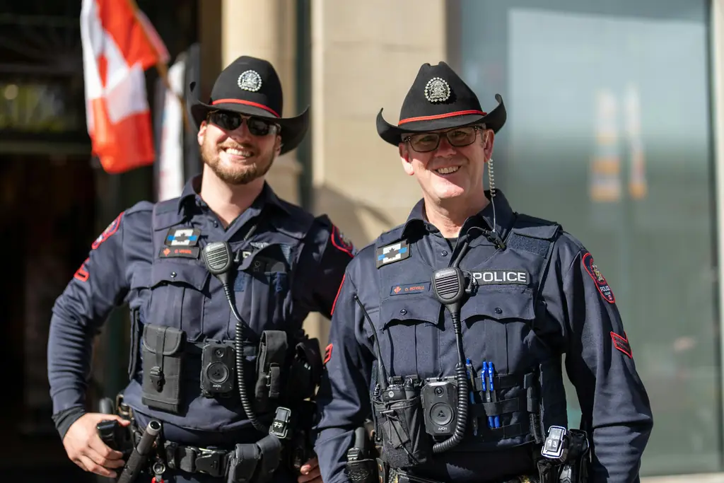 Deux policiers canadiens en uniforme devant un drapeau du Canada : le certificat de police exigé pour immigrer