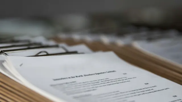 Des piles de documents agrafés sur un bureau : les pièces d'un dossier d'immigration