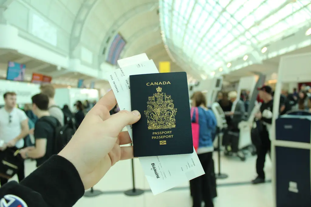 Une main tenant un passeport dans une file d’aéroport : conserver sa résidence permanente au Canada