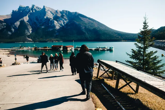 Des visiteurs marchent vers un lac turquoise au pied des Rocheuses canadiennes : les provinces qui choisissent elles-mêmes leurs immigrants